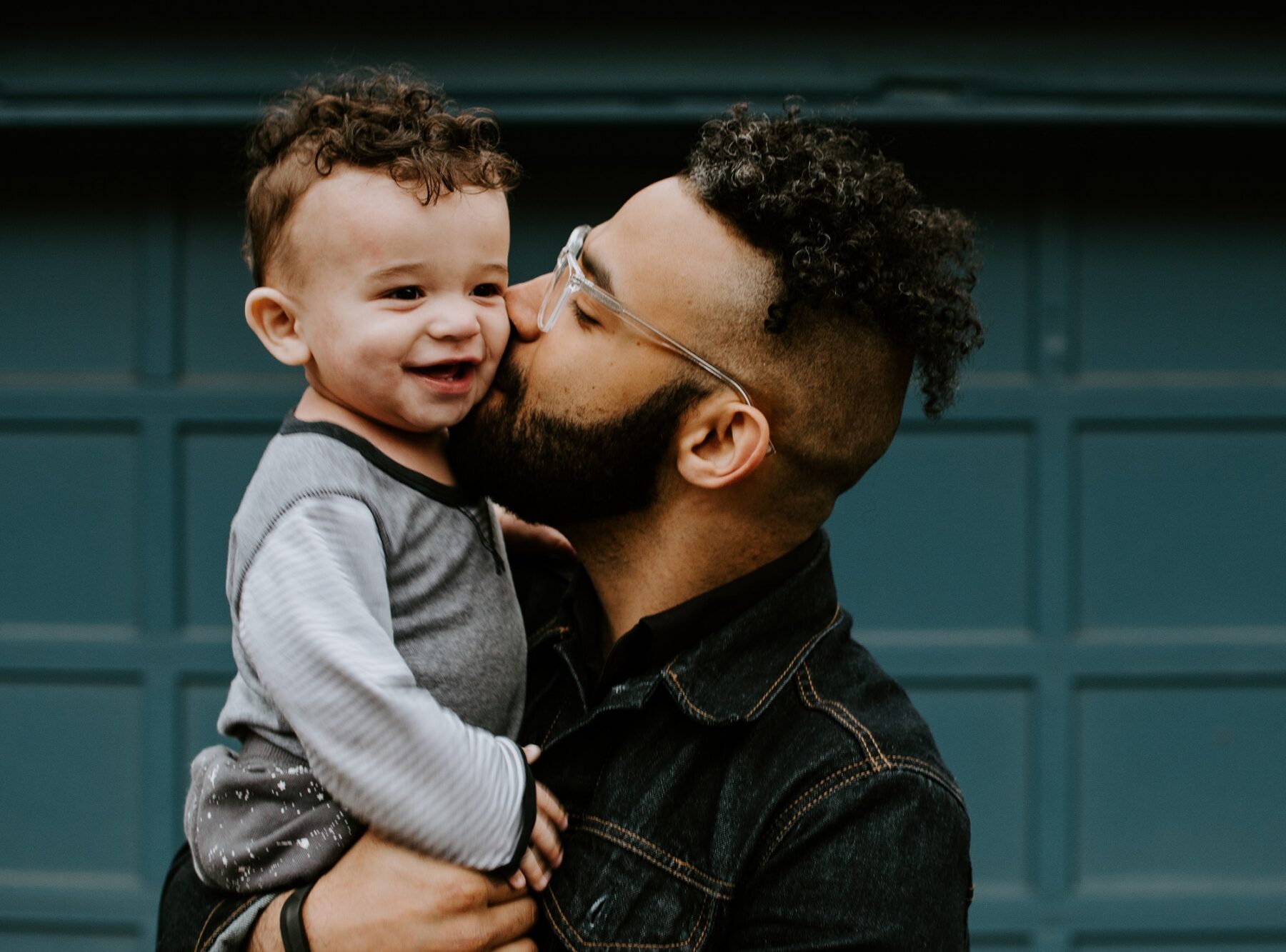 Young father kisses his baby boy on the cheek