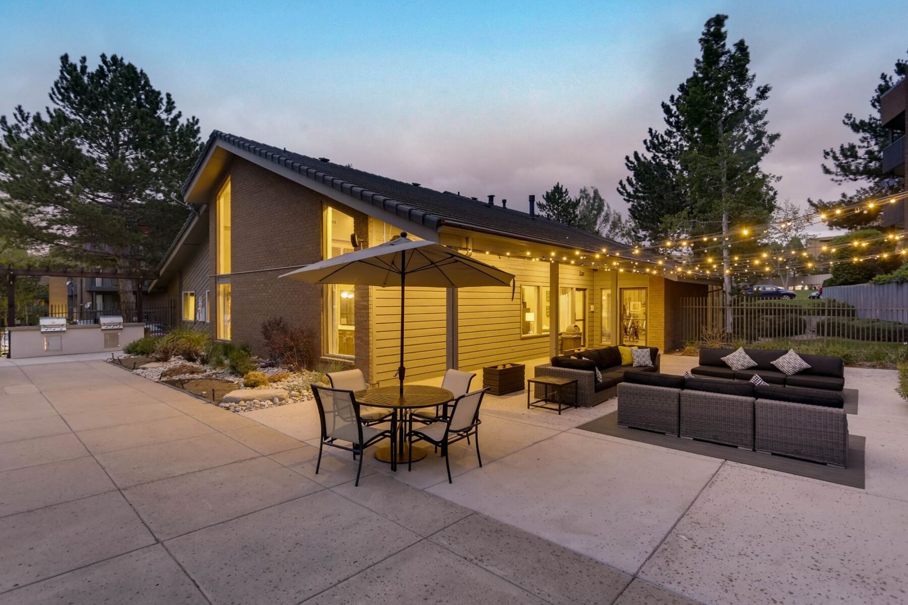 Clubhouse exterior with lounge seating, tables, string lights, and grills