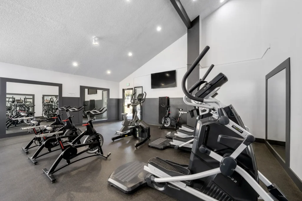 Indoor gym with cardio machines, designer lighting, television and tile flooring