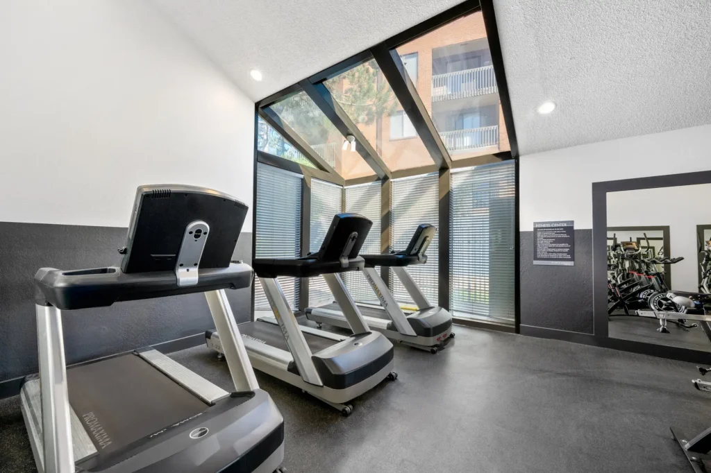 Indoor gym with cardio machines, designer lighting and tile flooring